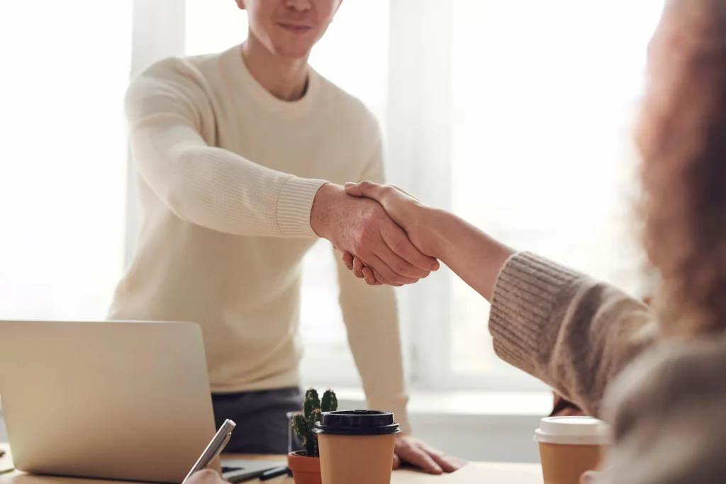 Man in casual attire shaking hands with an interviewer.