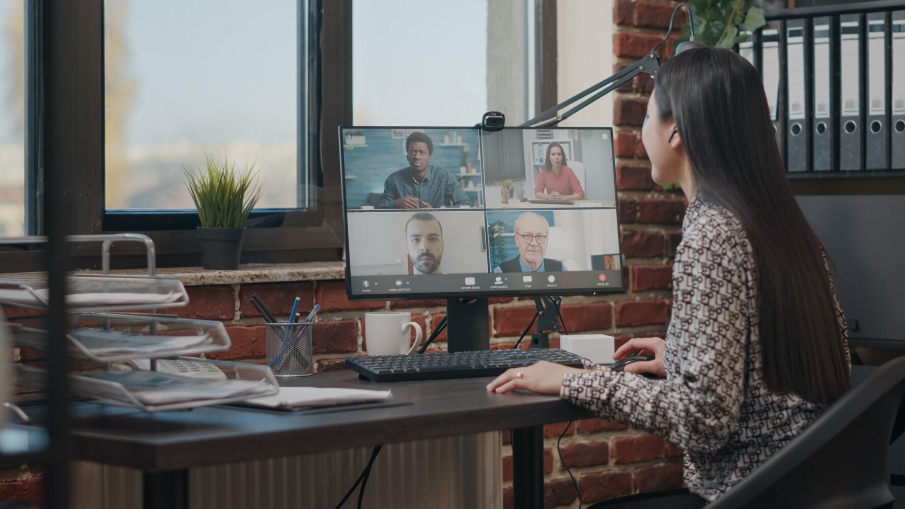 Team leader sitting in front of a desktop meeting virtually with remote team members.