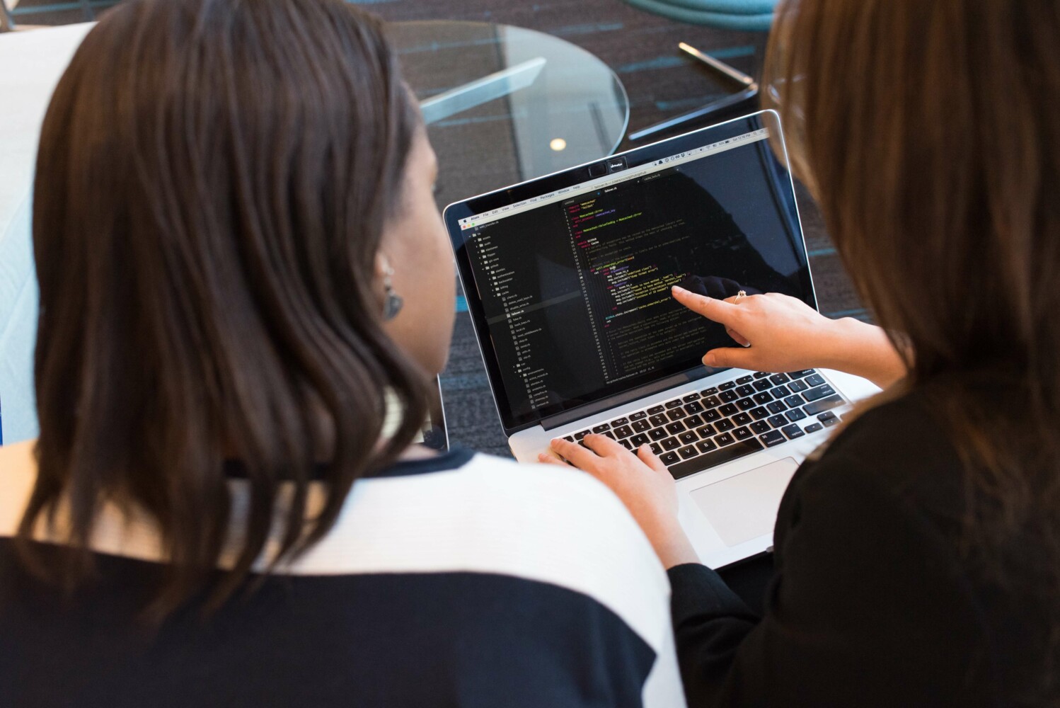 Two women developers conducting a code review on a laptop.